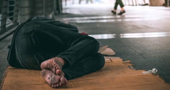 cerrar-pies-hombre-hogar-durmiendo-piso-sucio-calle-urbana-ciudad_28658-105